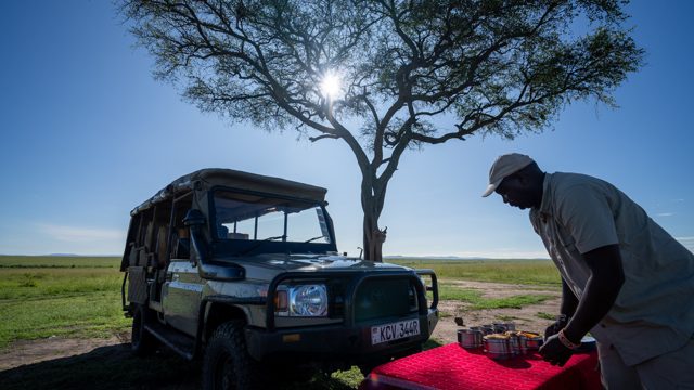 Bush breakfast setup with safari vehicle and staff