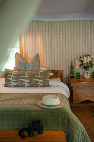 Tent interior with hat and binoculars on the bed
